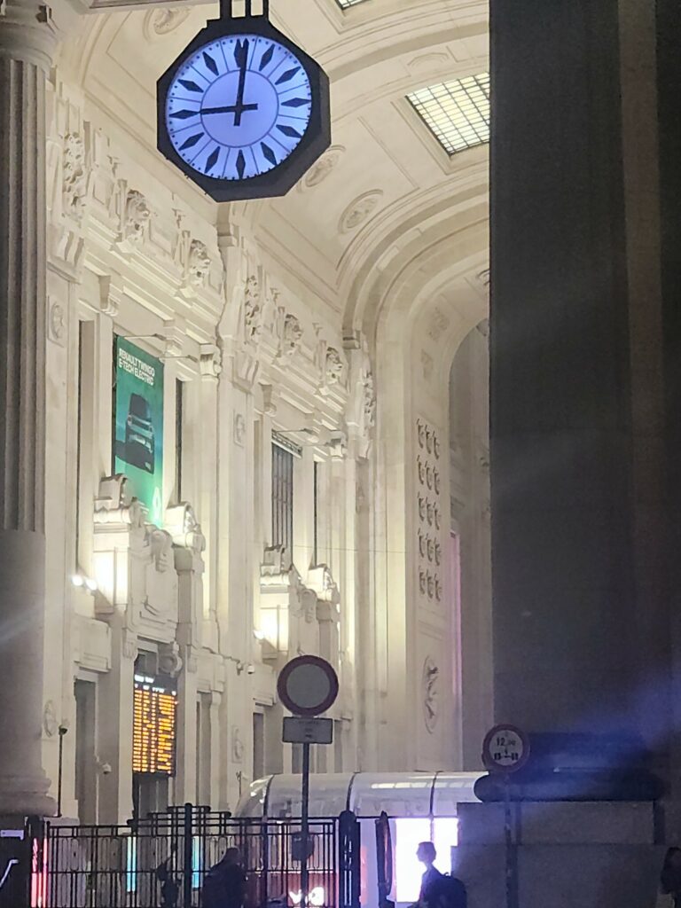 The blue illuminated clock in the atrium of Milan Central Station